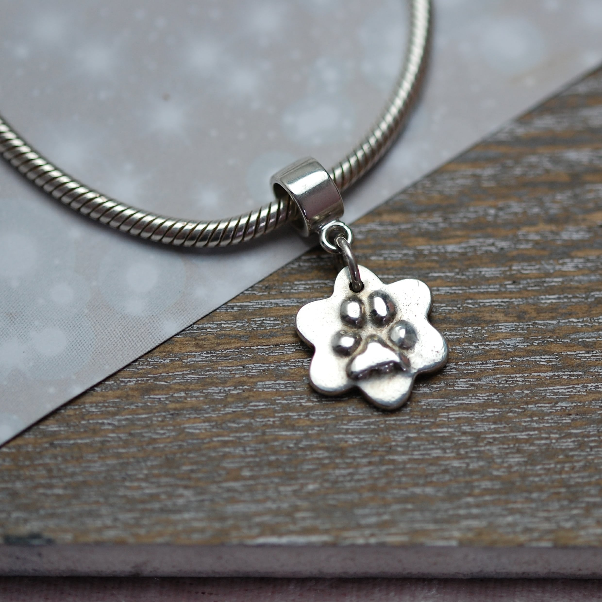 Small silver flower with raised paw print and charm carrier
