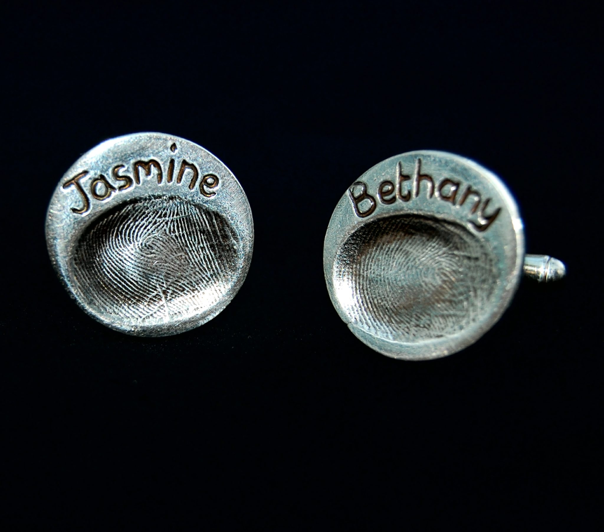 Circle shaped silver fingerprint cufflinks with names hand inscribed above the fingerprints.