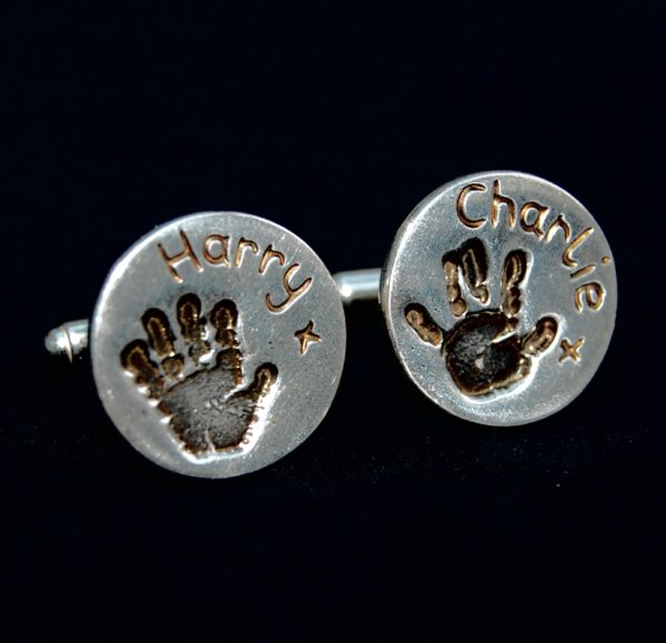 Circle shaped silver handprint cufflinks with names hand inscribed alongside the prints.