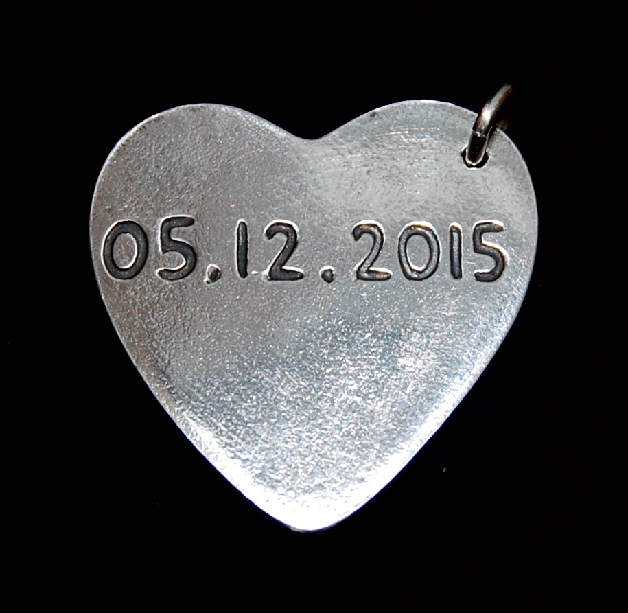 Special date hand inscribed on the back of a charm.