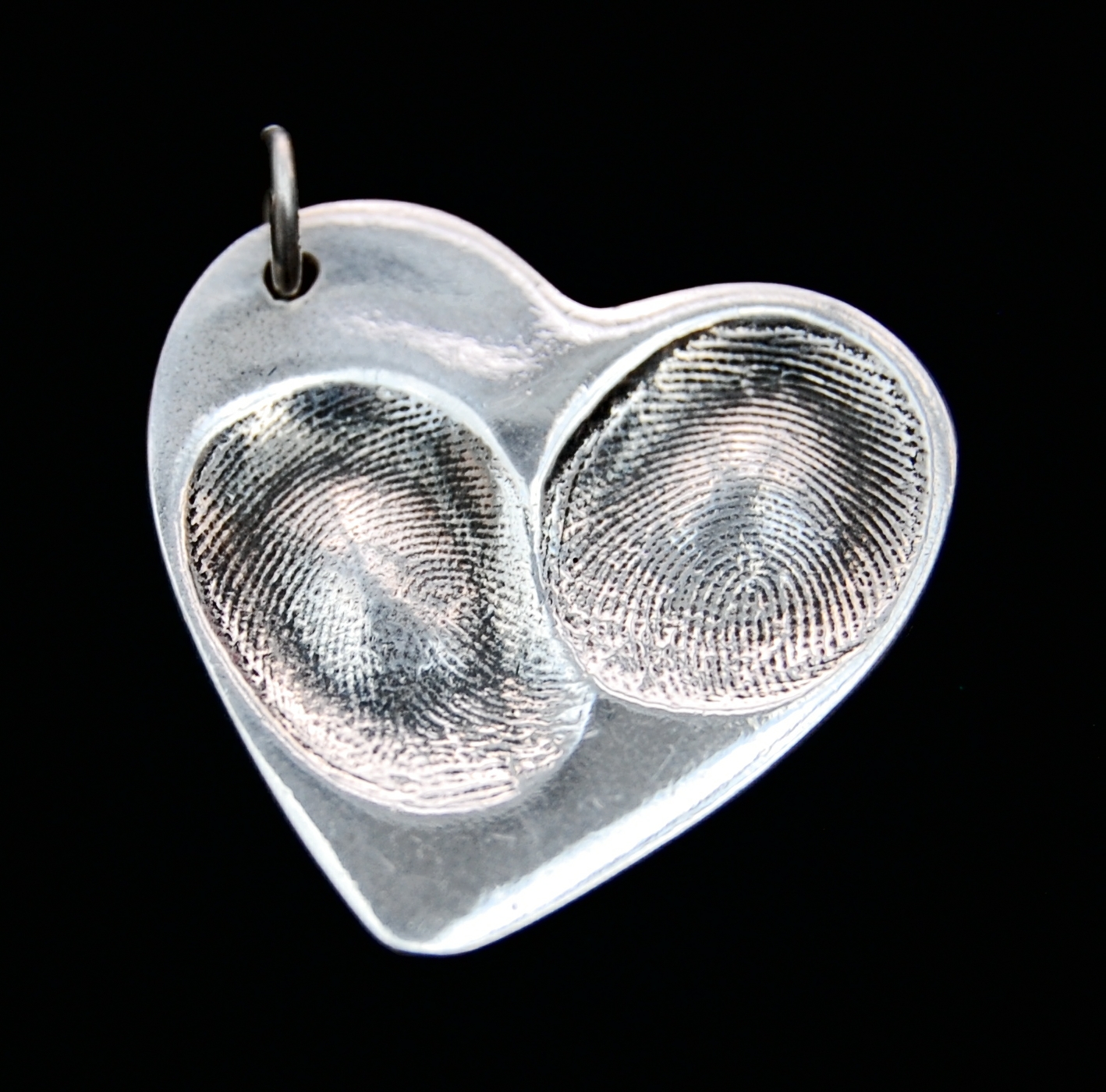 Large heart shaped fingerprint charm showcasing prints on the front and names hand inscribed on the back.