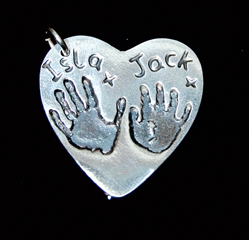Large silver heart charm with sibling handprints and names hand inscribed.