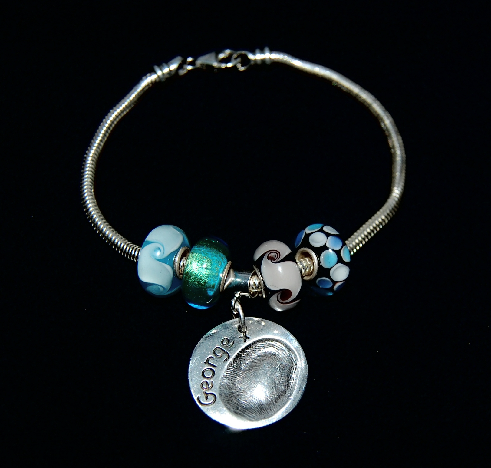 Regular circle shaped silver fingerprint charm presented on a charm carrier. Bracelet can be purchased separately from the Accessories section.