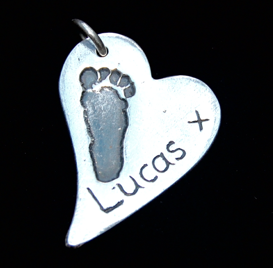 Regular silver curved heart footprint charm with name hand inscribed alongside the footprint.