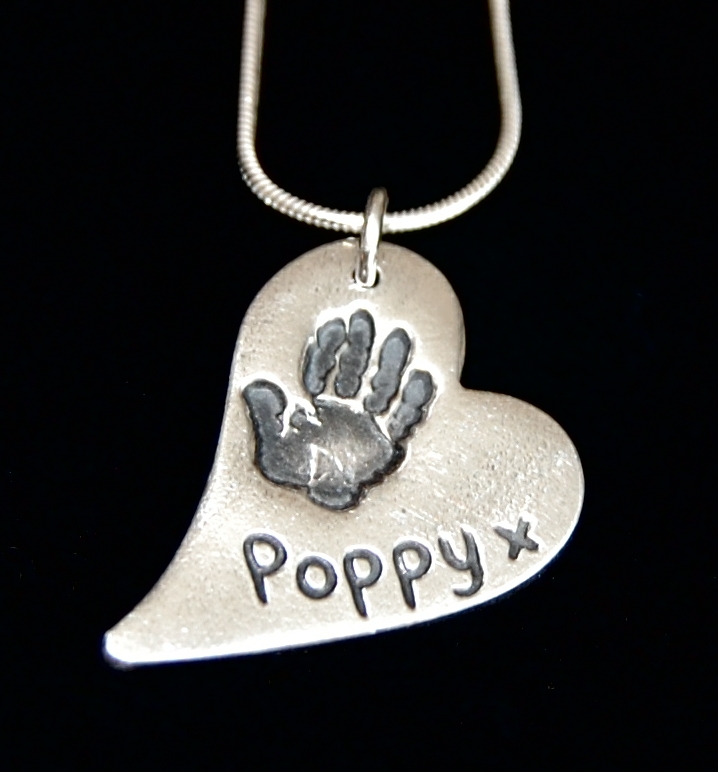 Regular silver curved heart handprint charm with name hand inscribed alongside the print.