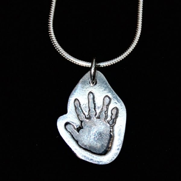 Regular silver charm cut by hand in the shape of the handprint. Name hand inscribed on the back.