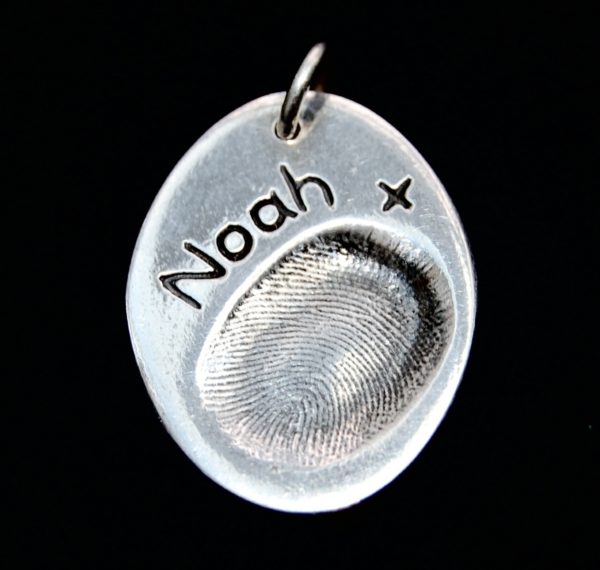 Regular oval shaped silver fingerprint charm with name hand inscribed alongside the fingerprint.