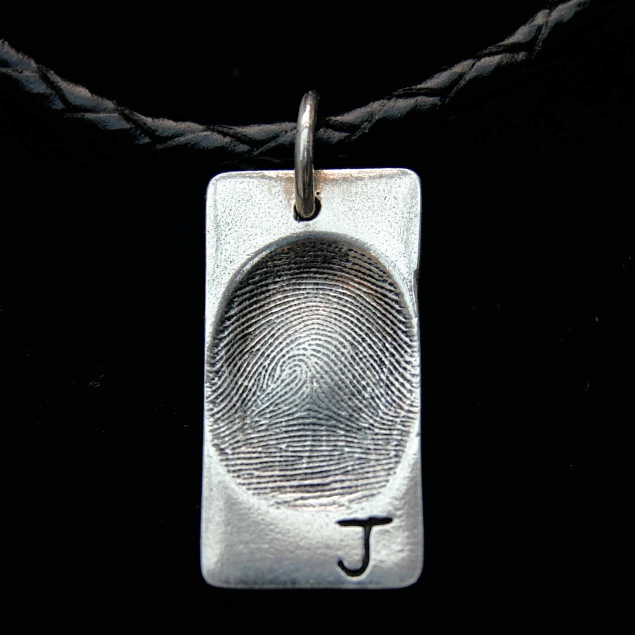 Regular rectangle shaped silver fingerprint charm with an initial inscribed on the front.