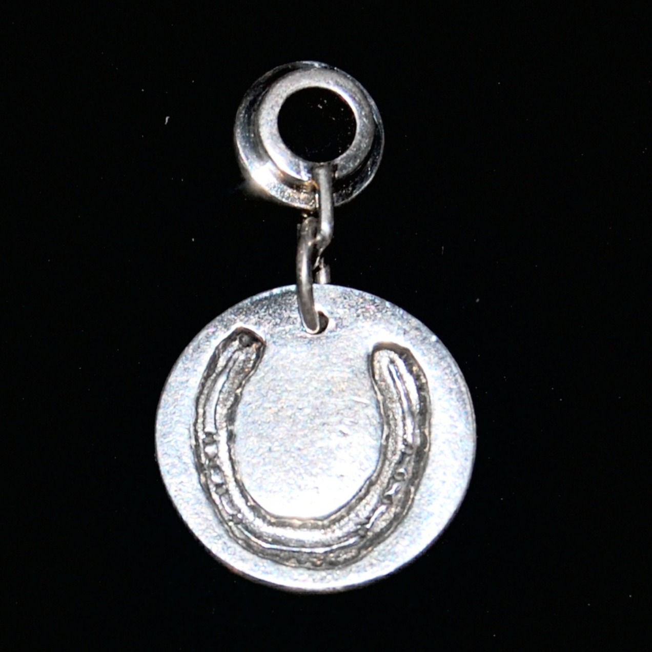 Regular silver circle charm with horse shoe imprint. Presented on a charm carrier ready to add to a bracelet.