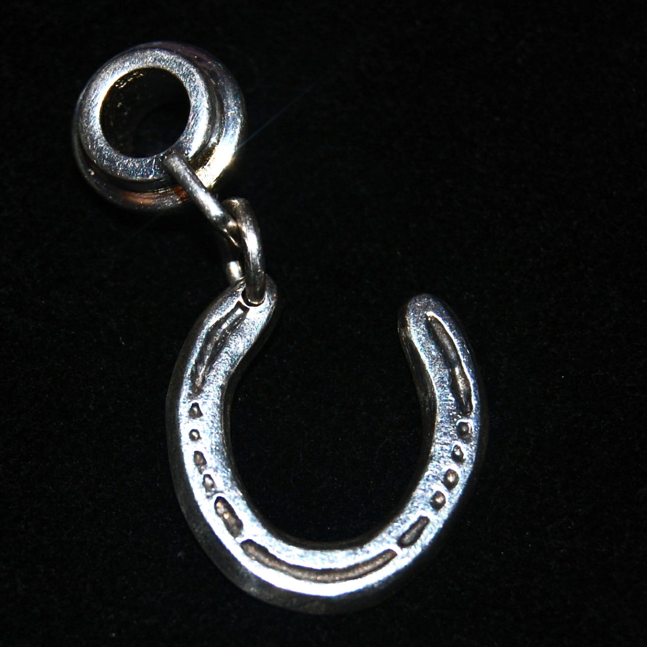Your own horse's unique shoe cut by hand in a silver charm, securely attached to a charm carrier ready to add to your bracelet.