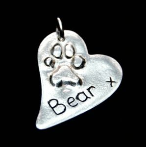 Silver charm with raised paw print.