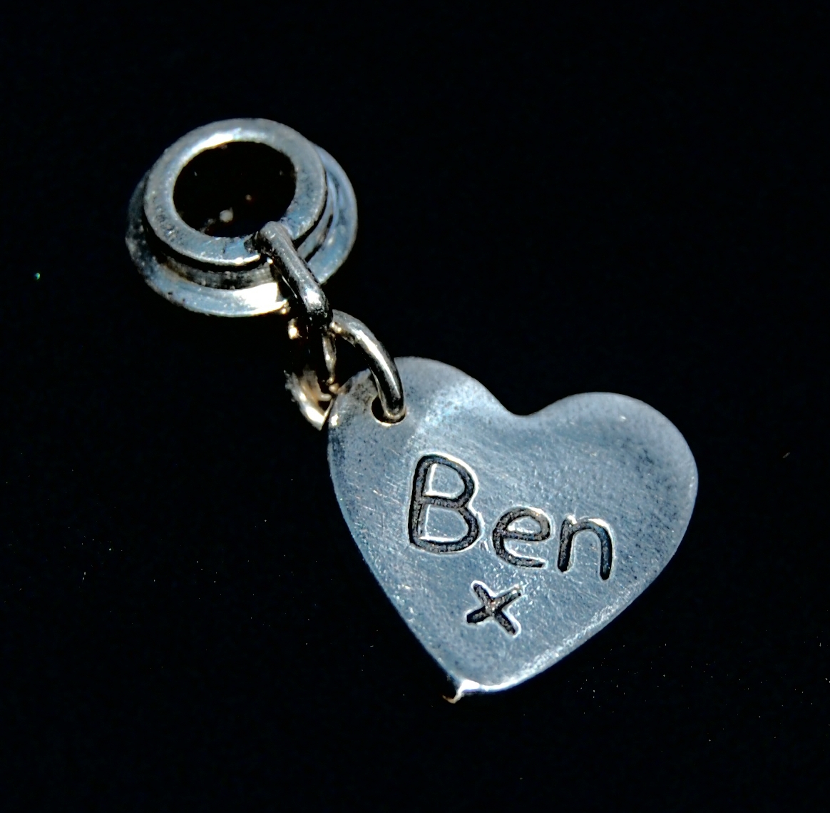 Small silver heart charm with name hand inscribed. Presented on a charm carrier ready to add to a bracelet or necklace.
