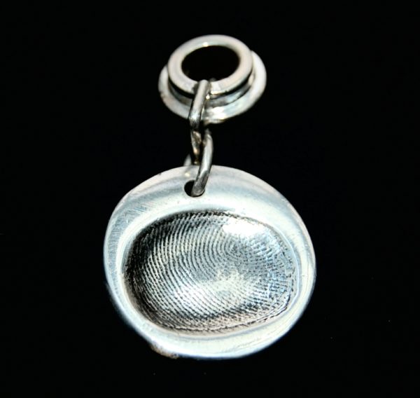 Small circle shaped silver fingerprint charm with name hand inscribed on the reverse. Charm secured attached to a charm carrier. Bracelets can be purchased separately.