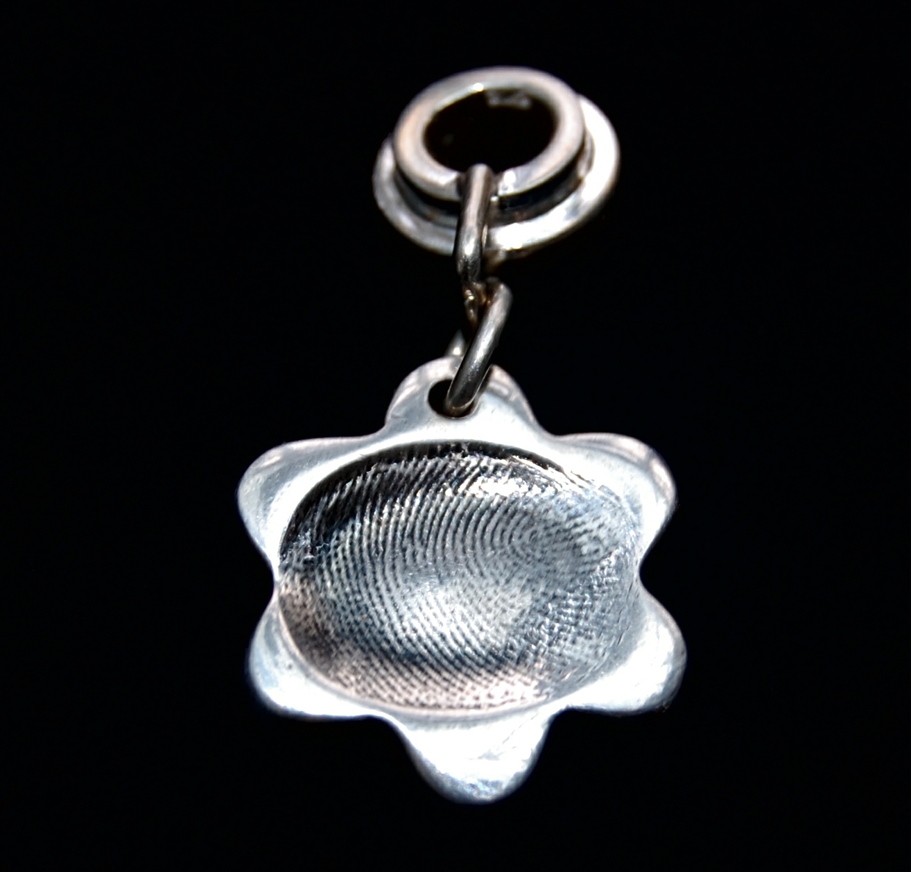 Small flower shaped silver fingerprint charm with name hand inscribed on the reverse. Charm secured attached to a charm carrier. Bracelets can be purchased separately.