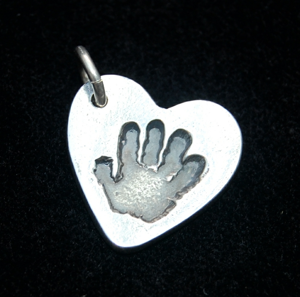 Small heart shaped silver handprint charm with name hand inscribed on the back.