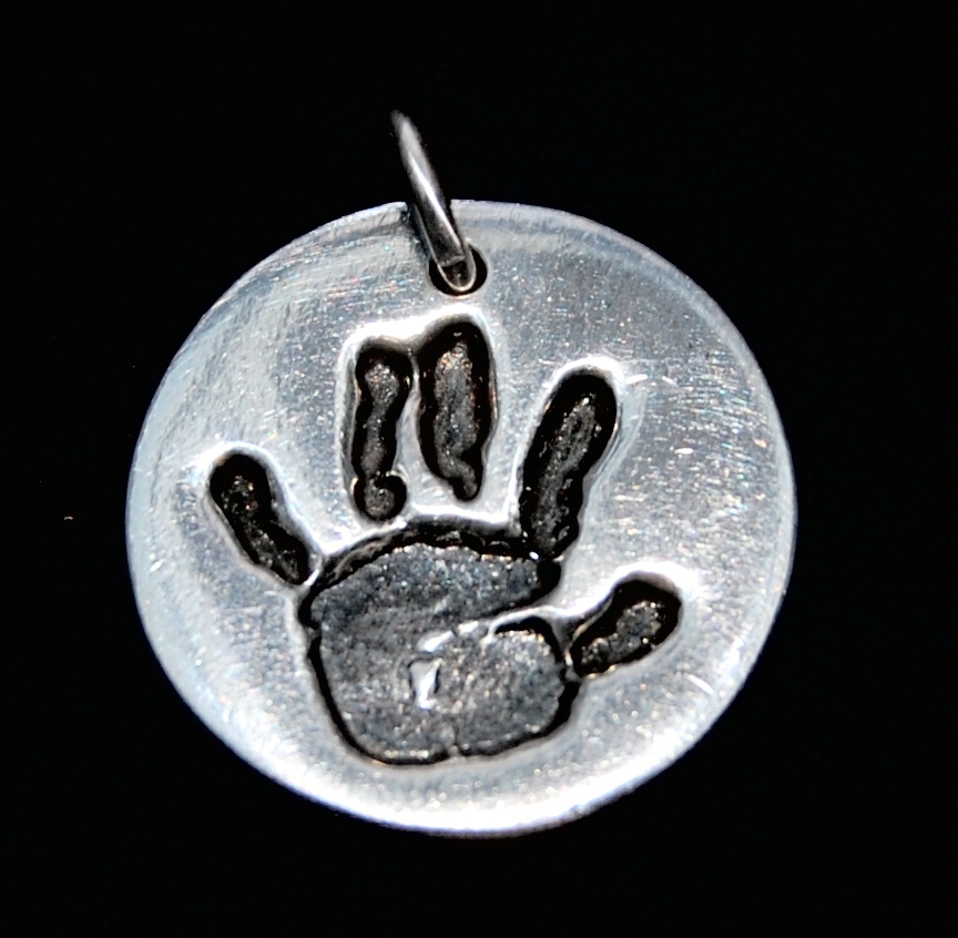 Small silver circle handprint charm with name hand inscribed on the back.