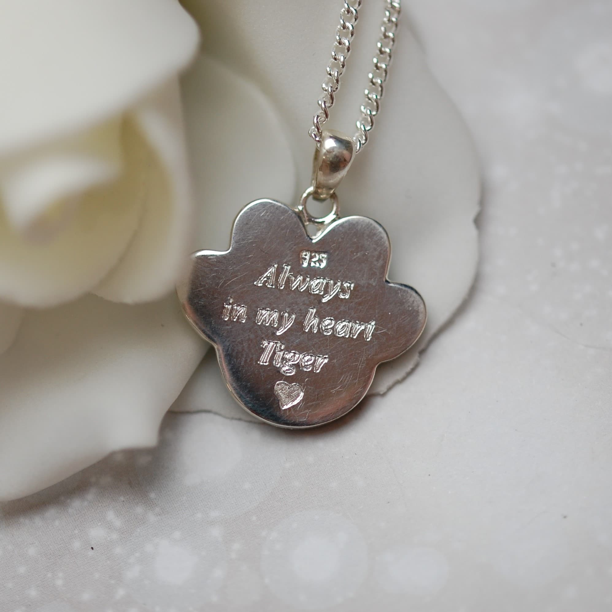 Pet name and message engraved on silver paw print pendant with pet fur or cremation ashes