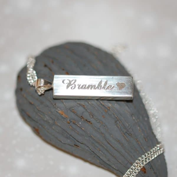 Pet name and heart engraved on the back of silver rectangle pendant with pet fur or cremation ashes