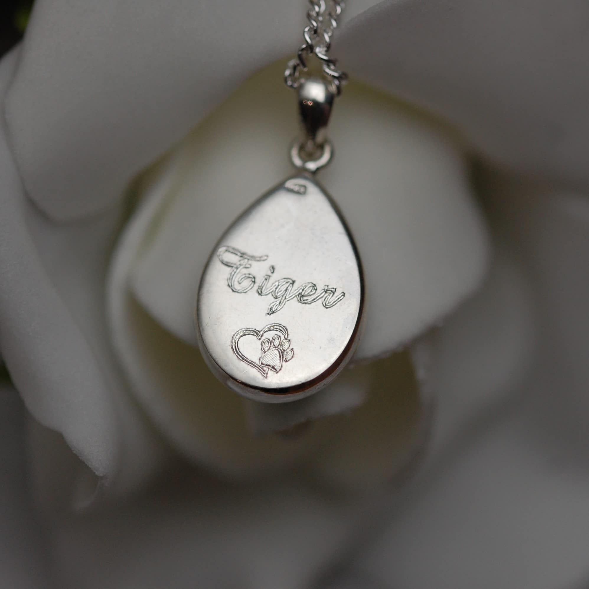 Pet name inscribed on the back of a silver tear drop pendant with pet fur or cremation ashes