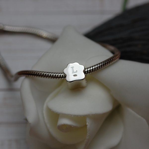 Initial engraved on the back of a silver paw print charm bead with pet ashes
