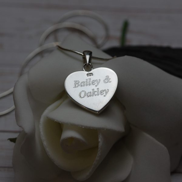 Pet names engraved on the back of silver heart necklace with pet cremation ashes