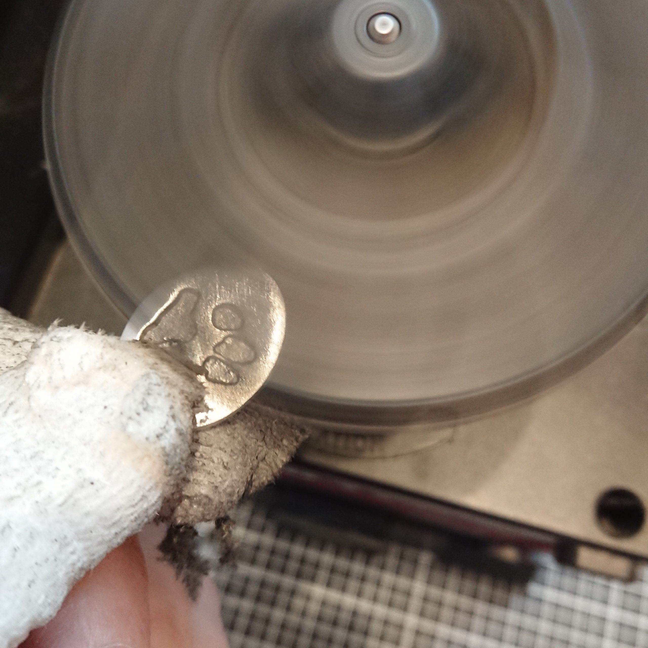 silver paw print cufflink being polished on a jool tool